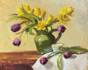 Vibrant oil painting of golden daffodils and rich purple tulips in a green jug, accompanied by a delicate teacup and a softly draped cloth. Impressionist floral still life with bold brushstrokes and warm tones.