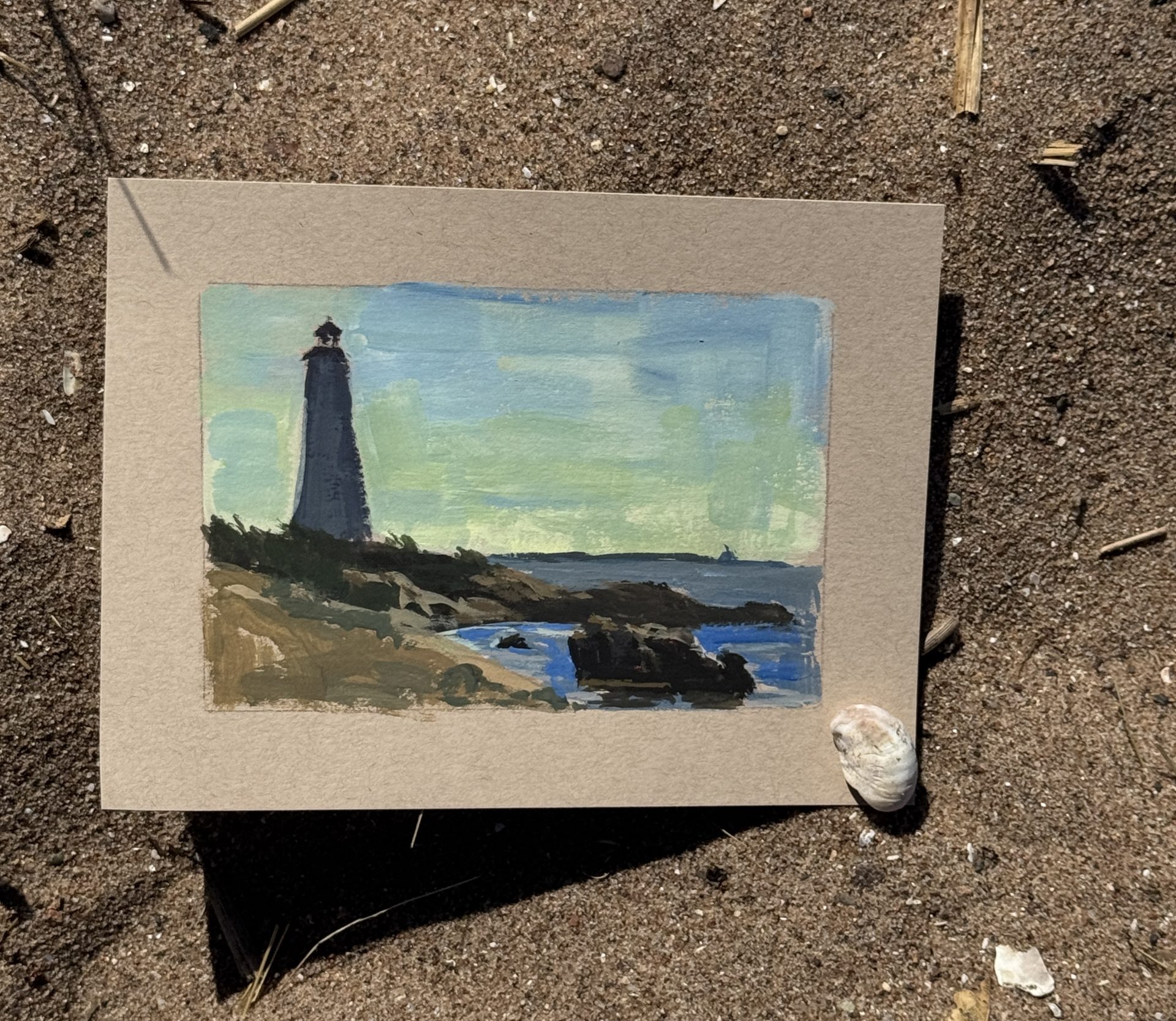 Lighthouse by the Shore, horizontal gouache plein air lighthouse painting by Kelli Folsom, showing a rocky coastline, sparkling water, and a sunlit lighthouse under a clear midday sky.