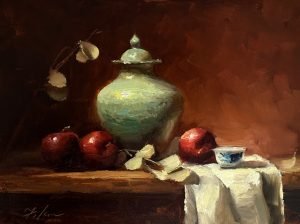 Still life oil painting of red apples and a turquoise ceramic jar with delicate flowers on a wooden table against a warm brown background