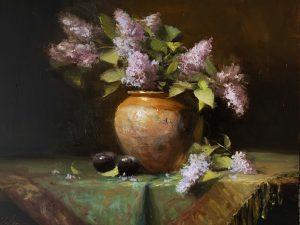 Original oil still life painting of lilac blossoms in a warm ochre pottery vase with dark plums on a draped table against a moody background.